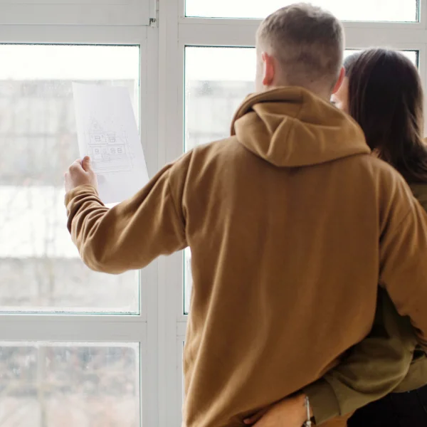 Un homme et une femme examinent un plan sur une fenêtre, discutant des détails du projet.