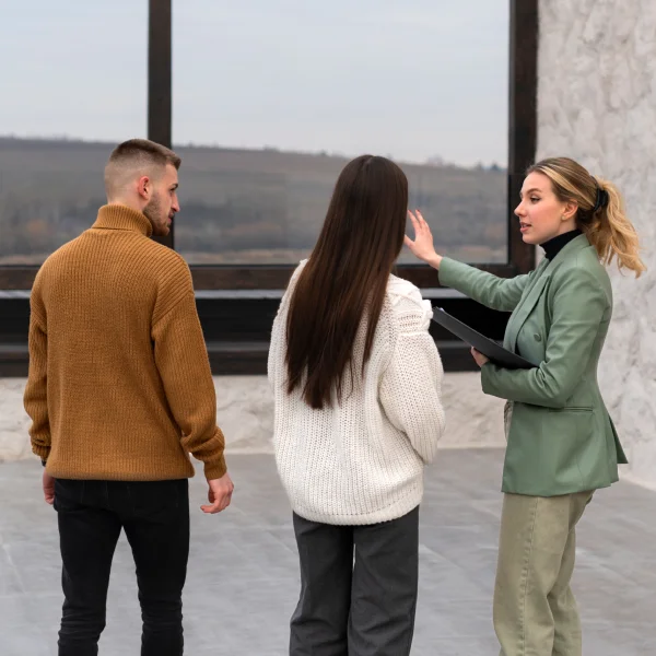 Trois personnes se tiennent devant un bâtiment, discutant ensemble dans un cadre urbain.