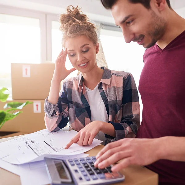 Un homme et une femme regardent un calculateur devant des boîtes, discutant de la valeur de leur maison.