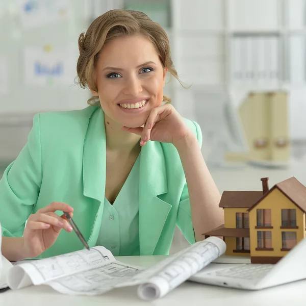Une femme assise à un bureau avec un ordinateur portable, réfléchissant à la valeur de sa maison.
